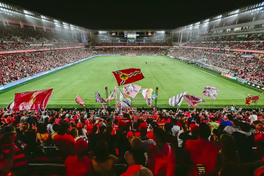 Photo of a crowded statium of soccer fans cheering on a game